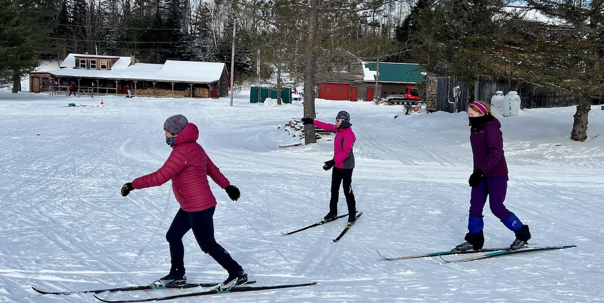 A ski coach working with two women on nordic skis